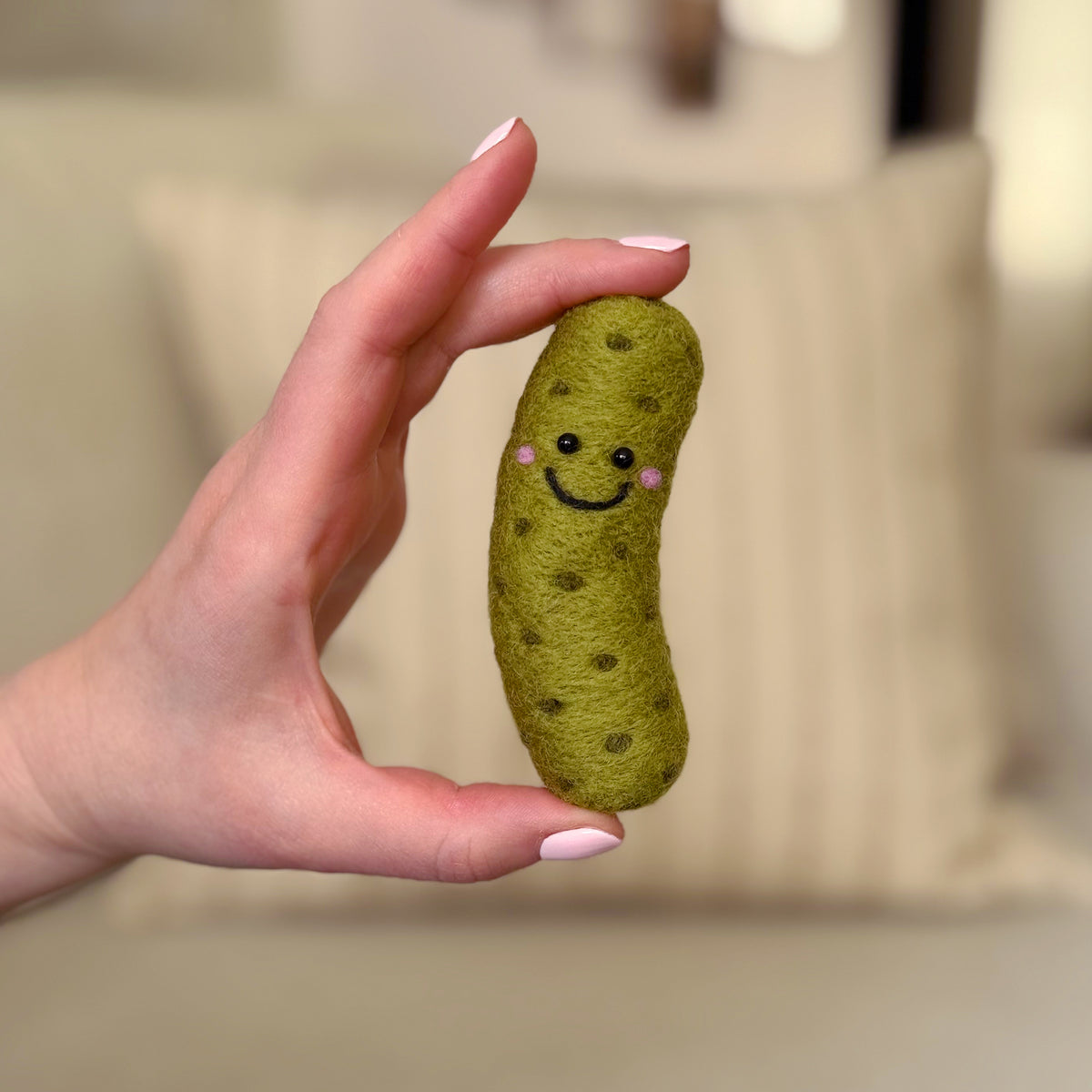 Hand holding the finished The Big Dill Pickle Feltie, a beginner-friendly needle-felting project from Feltie Kits