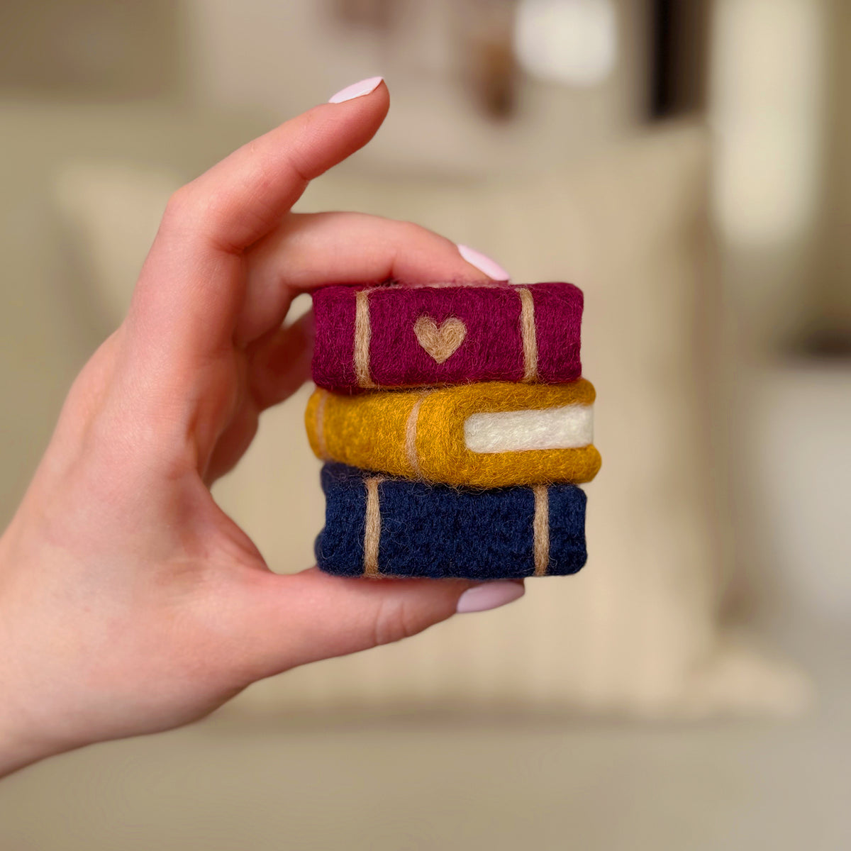 Hand holding the finished Storybook Stack Feltie, a beginner-friendly needle-felting project from Feltie Kits