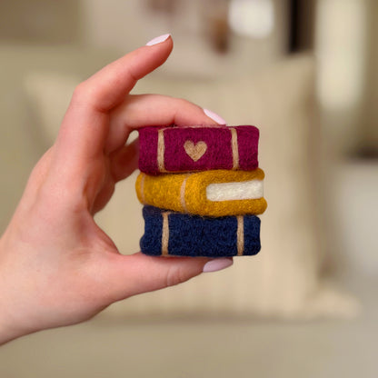 Hand holding the finished Storybook Stack Feltie, a beginner-friendly needle-felting project from Feltie Kits
