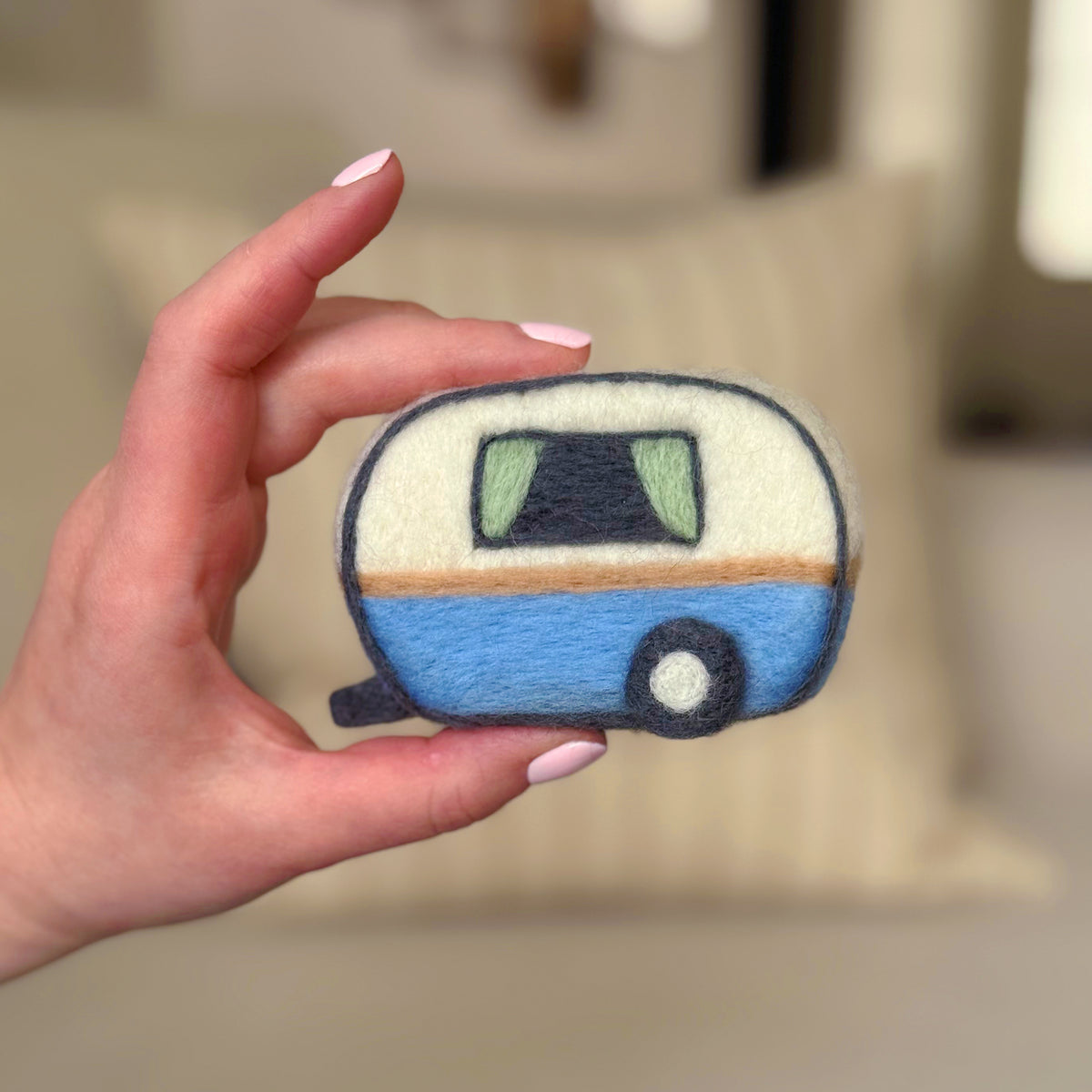 Hand holding the back of the finished Happy Camper Feltie, a beginner-friendly needle-felting project from Feltie Kits