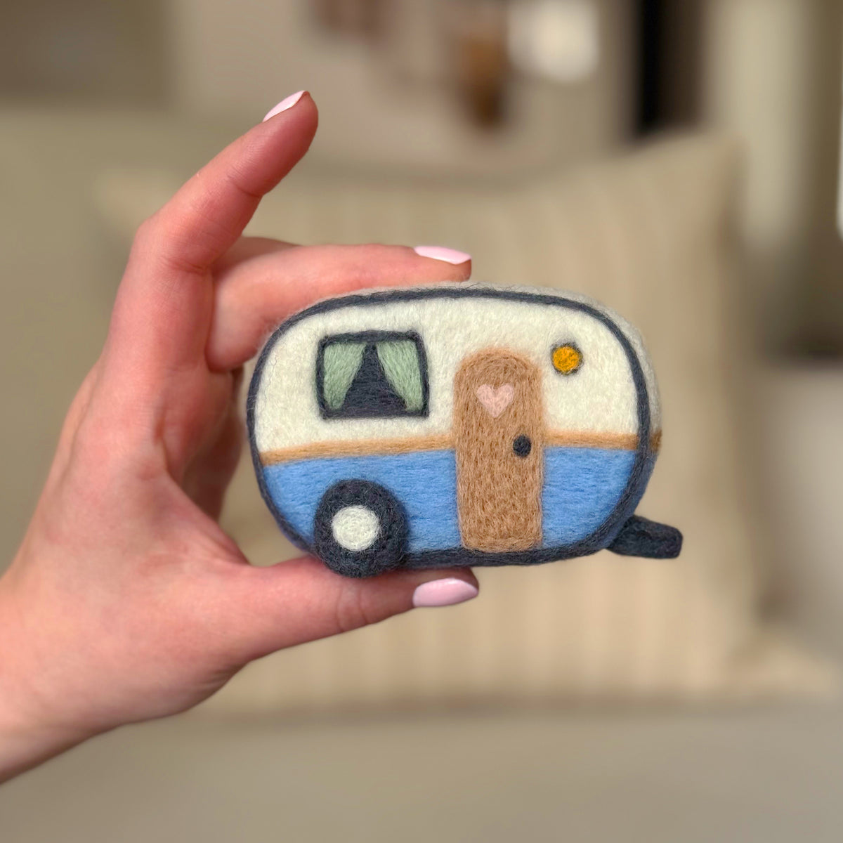 Hand holding the front of the finished Happy Camper Feltie, a beginner-friendly needle-felting project from Feltie Kits