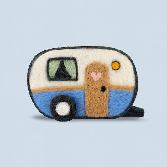 Finished Happy Camper Feltie from Feltie Kits, showing a handmade felt camper trailer with blue and cream wool details, a heart-shaped door accent, and cozy vintage-inspired design.