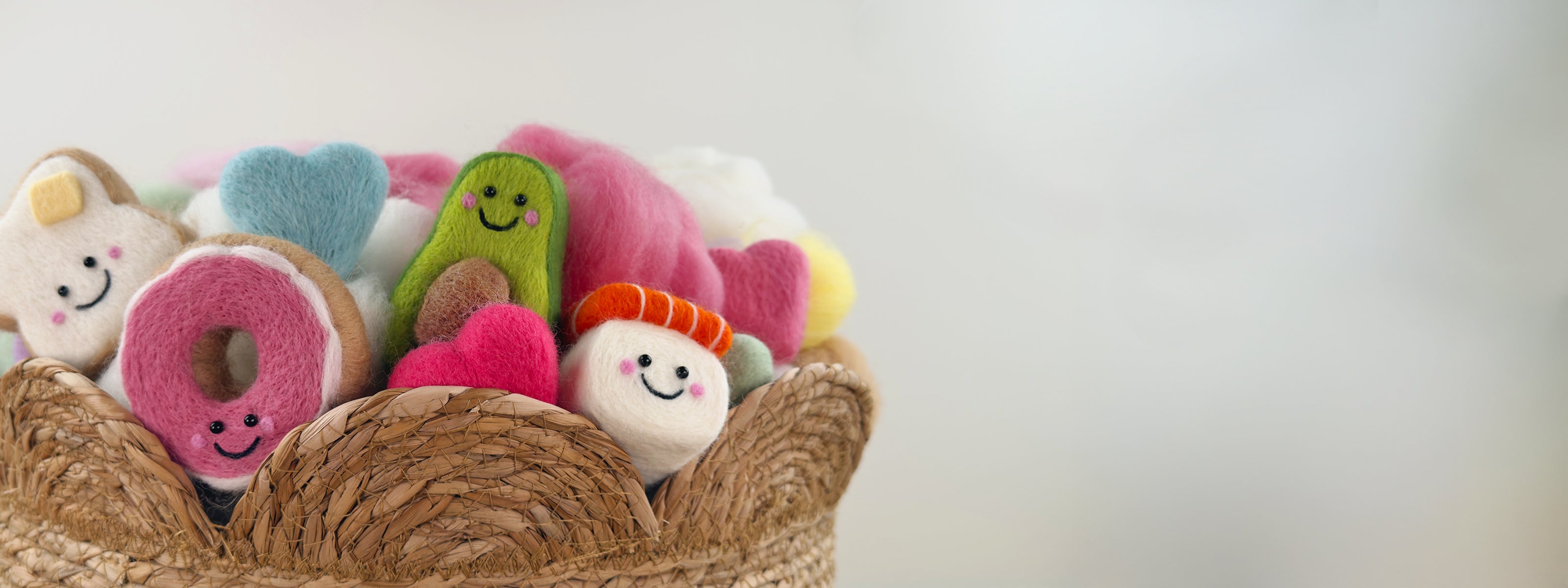 Basket filled with cute needle-felted characters including a donut, toastie, avocado, & sushi, displayed for Feltie Kits.