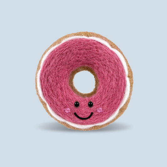 Finished Pink Glazed Donut Feltie made from the Feltie Kits needle felting kit, showing the donut with pink wool, white glaze and smile. 