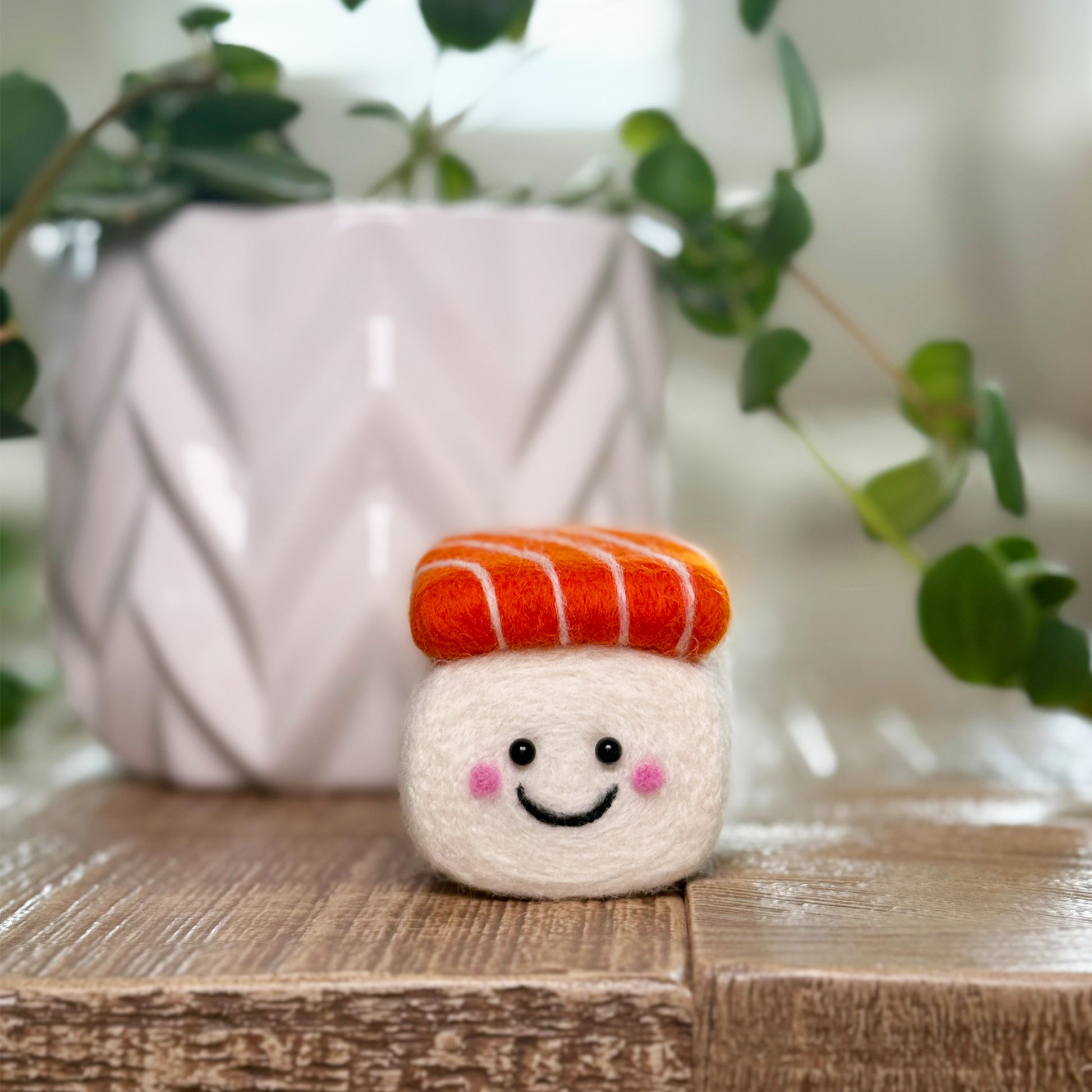 Finished salmon sushi Feltie from the Feltie Kits needle-felting project, shown as a cute wool sculpture on a wooden surface.